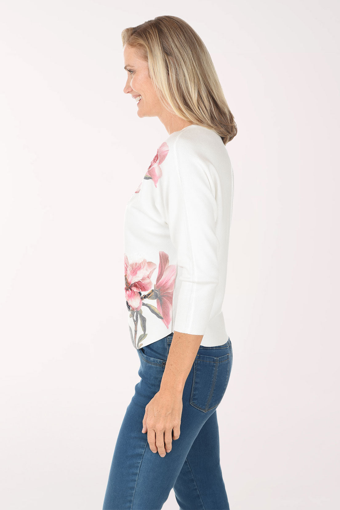 Woman wearing a white sweater with pink floral patterns on a white background