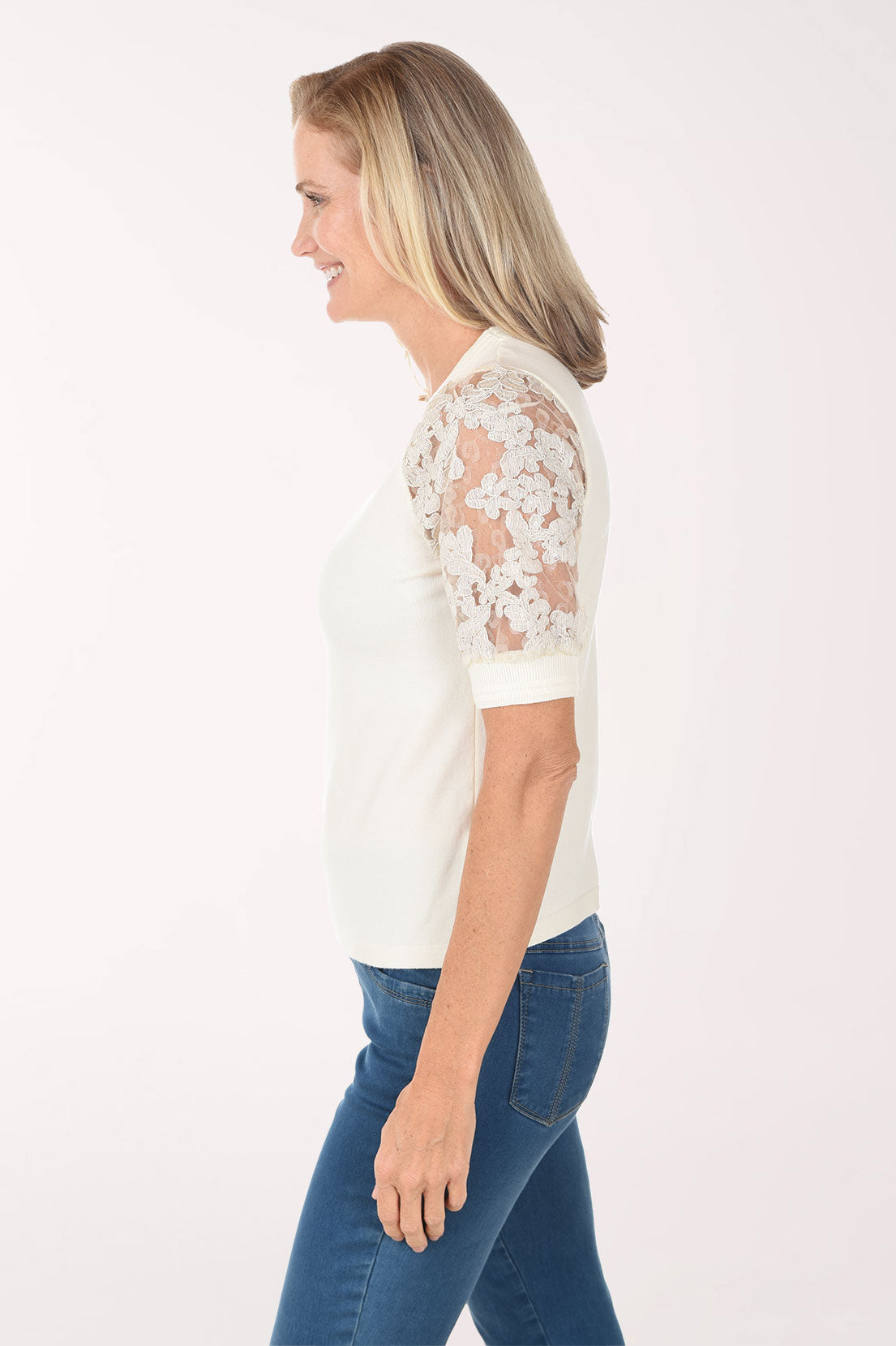 Woman wearing a white blouse with lace sleeves and blue jeans on a white background