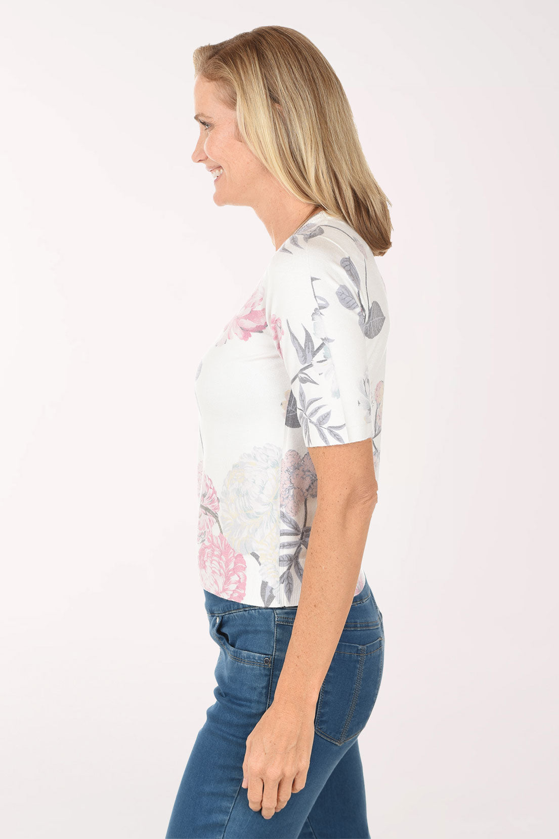 Woman wearing a floral top and blue jeans on a white background