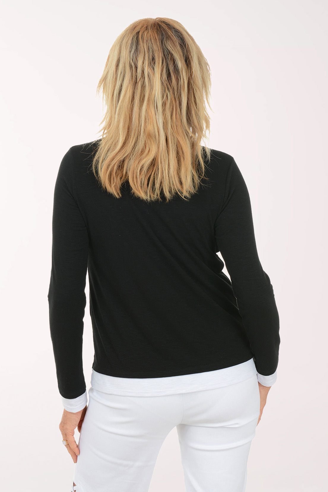Woman wearing a black long-sleeve top and white pants on a white background