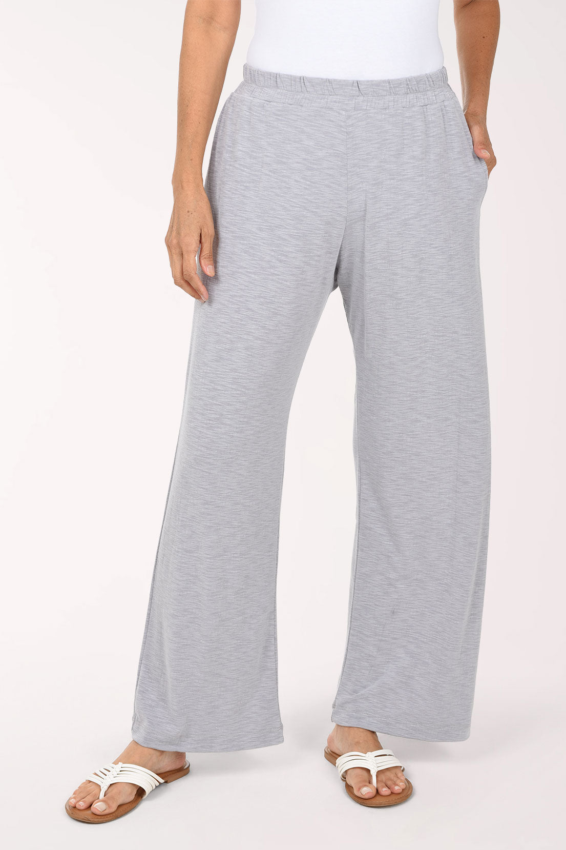 A person wearing heathered grey wide-leg pants with an elastic waistband and side pockets, paired with a white top and flat sandals, photographed against a plain light background.