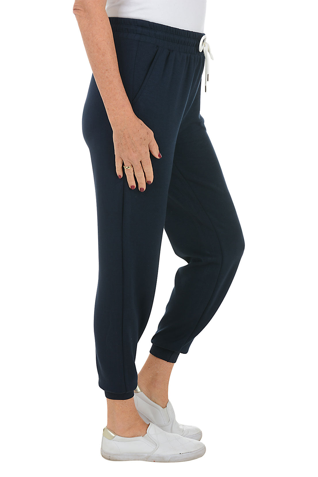 A side shot of a model wearing a ankle-length navy blue jogger pants with an elastic waistband and drawstring, featuring dual front pockets and ribbed cuff on hemline.