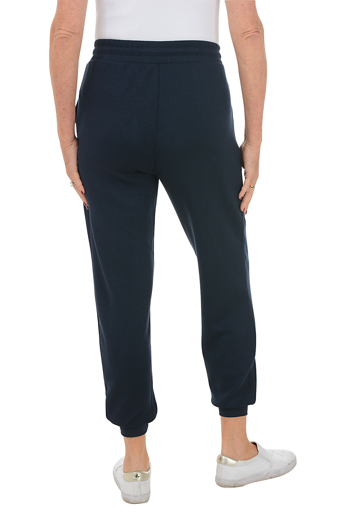 A back shot of a model wearing a ankle-length navy blue jogger pants with an elastic waistband and drawstring, featuring dual front pockets and ribbed cuff on hemline.