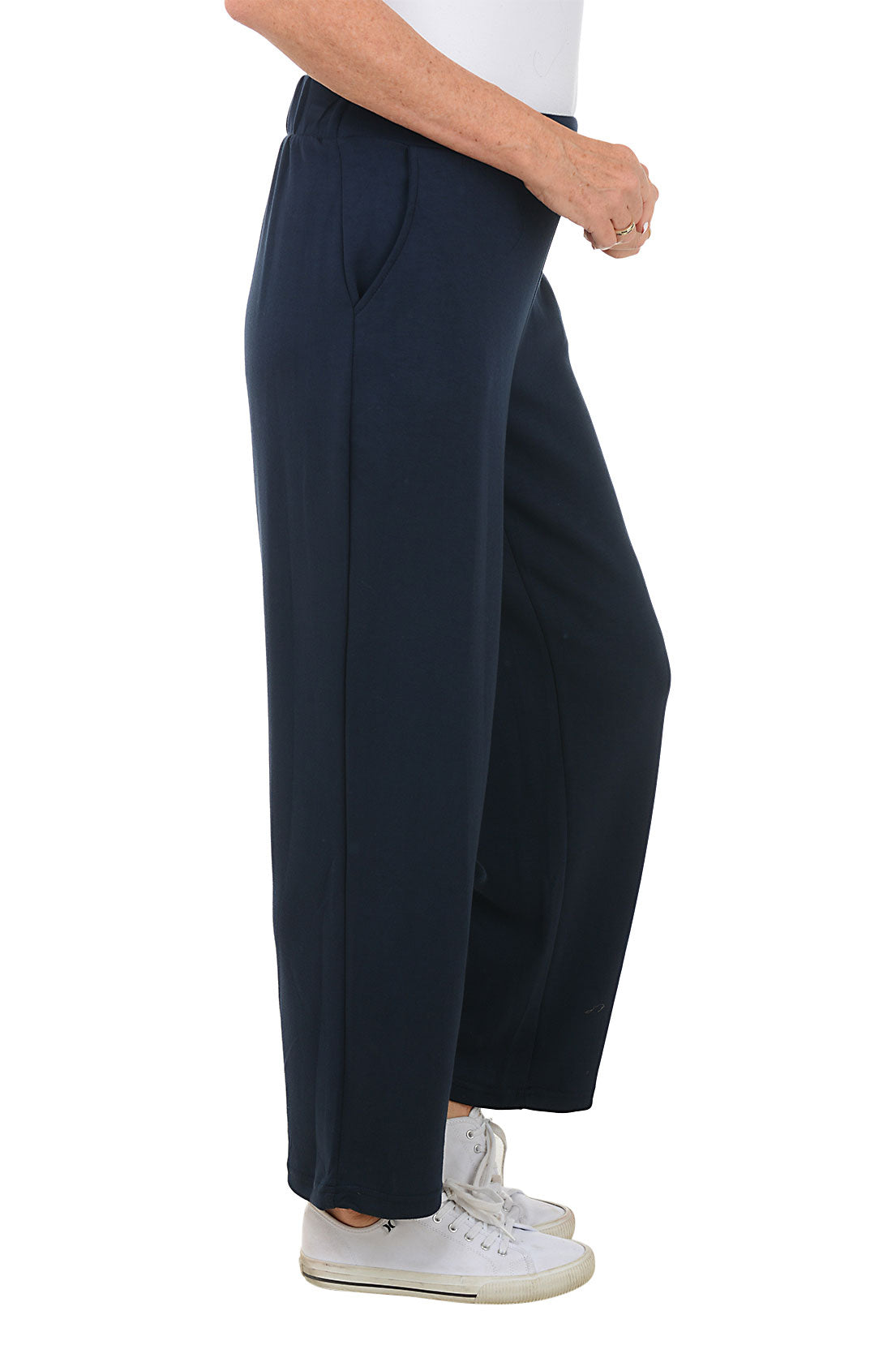 A side shot of a model wearing navy wide leg lounge pants with an elasticized waistband and dual front pockets, paired with white sneakers.
