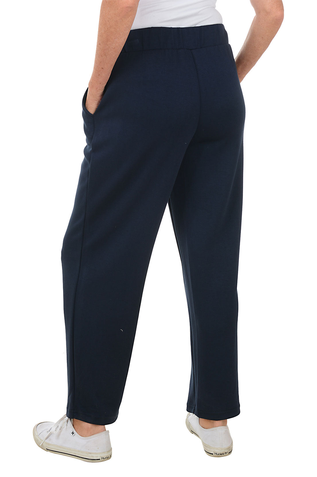A back shot of a model wearing navy wide leg lounge pants with an elasticized waistband and dual front pockets, paired with white sneakers.