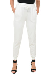 A front shot of a model wearing a pair of white jogger pants with an elastic waistband, adjustable drawstring, and faux pearl embellishment on the front pockets. The pants feature a ribbed cuff on the hemline and are flat-backed.