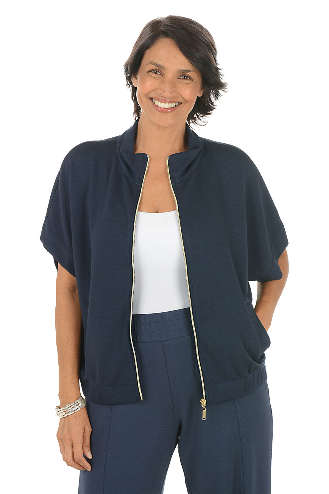 Woman wearing a navy blue zip-up top with a white background. Unzipped.
