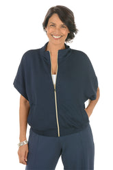 Woman wearing a navy blue zip-up top with a white background.