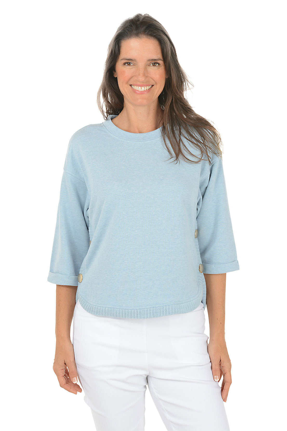 Woman wearing a light blue sweater and white pants on a white background
