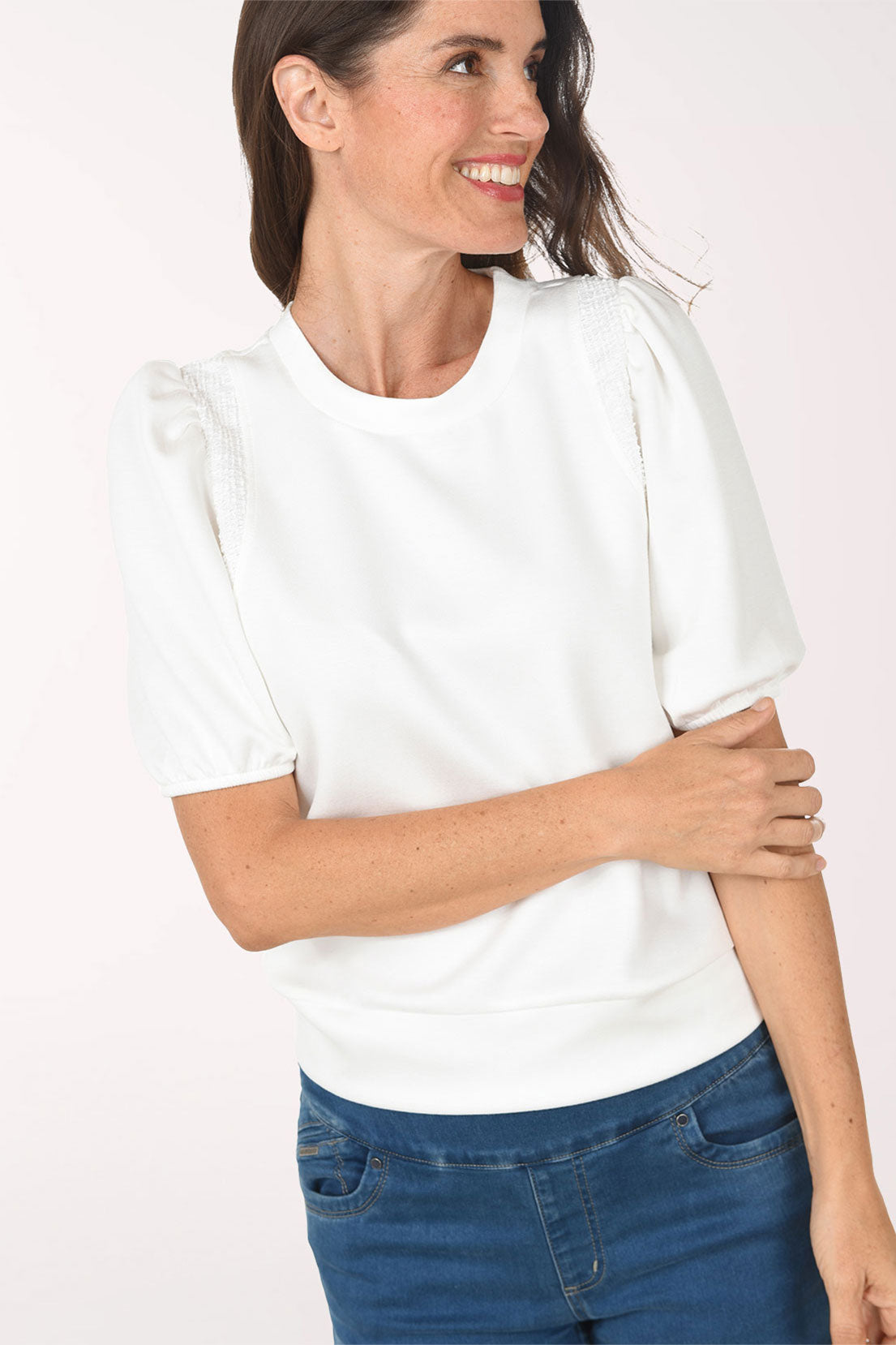 Woman wearing a white blouse and blue jeans on a white background
