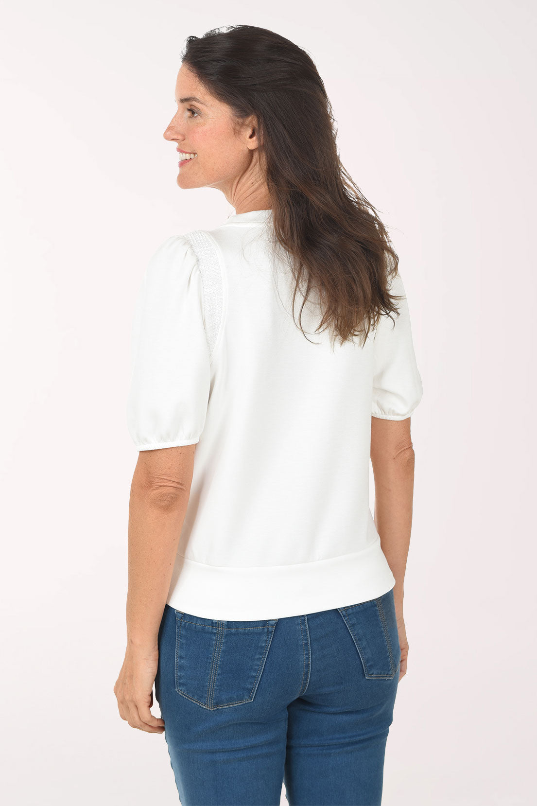 Woman wearing a white blouse and blue jeans on a white background