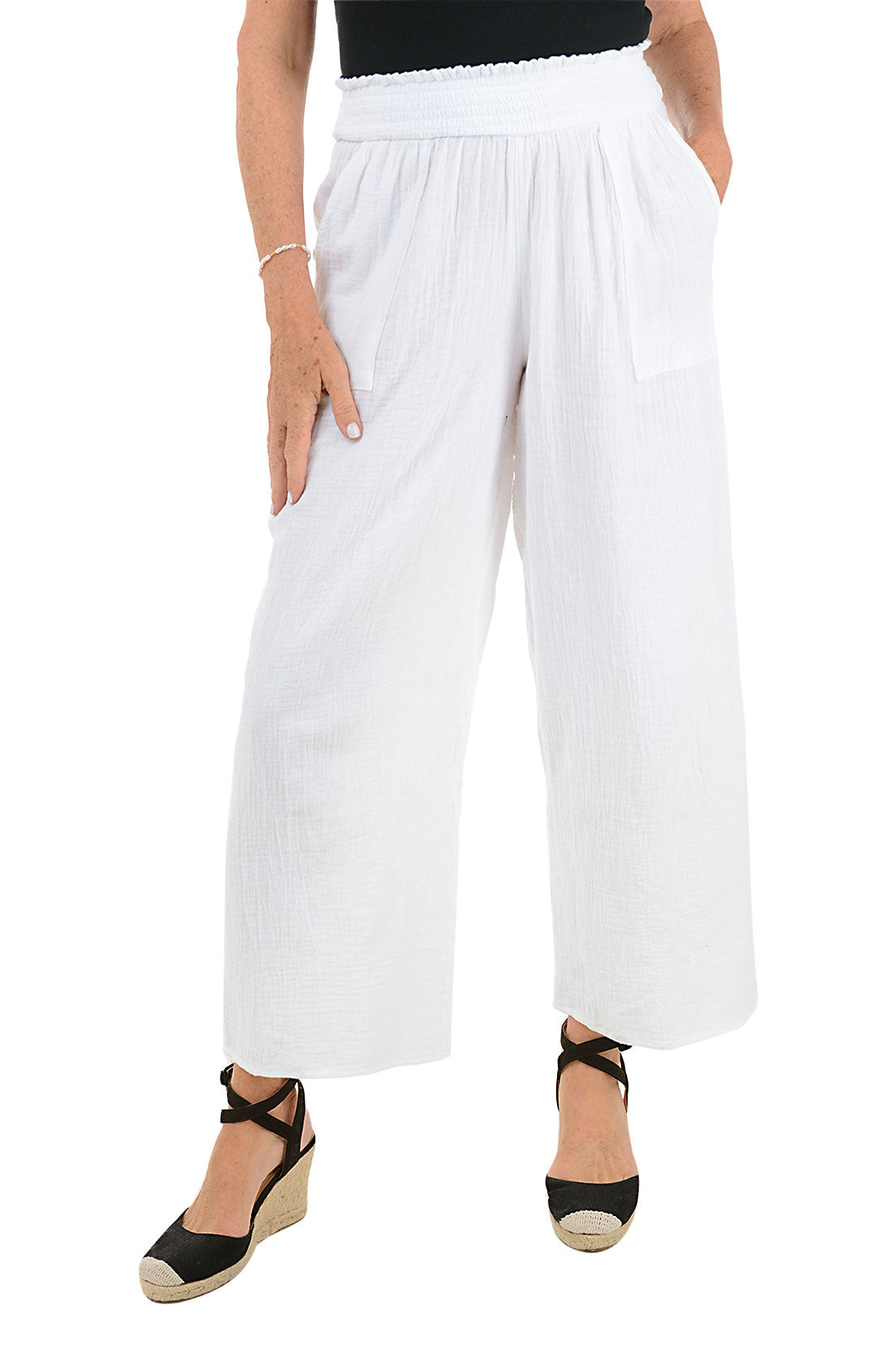 A front shot of a model wearing a pair of white wide leg cotton gauze lounge pants with a smocked stretch waistband and dual front patch pockets.