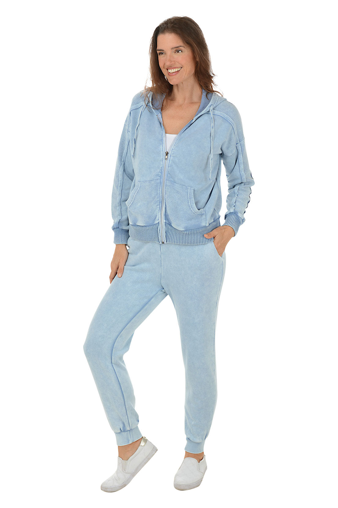 A full length shot of a model wearing light blue mineral wash French terry joggers with a wide ribbed waistband and ribbed ankle cuffs, paired with white sneakers.