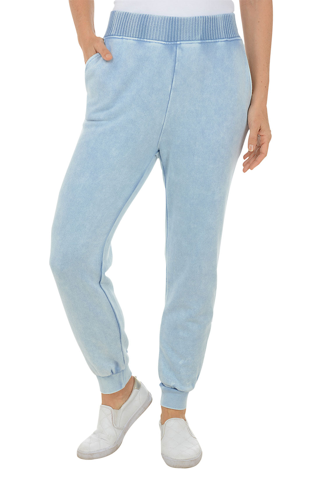 A front shot of a model wearing light blue mineral wash French terry joggers with a wide ribbed waistband and ribbed ankle cuffs, paired with white sneakers.