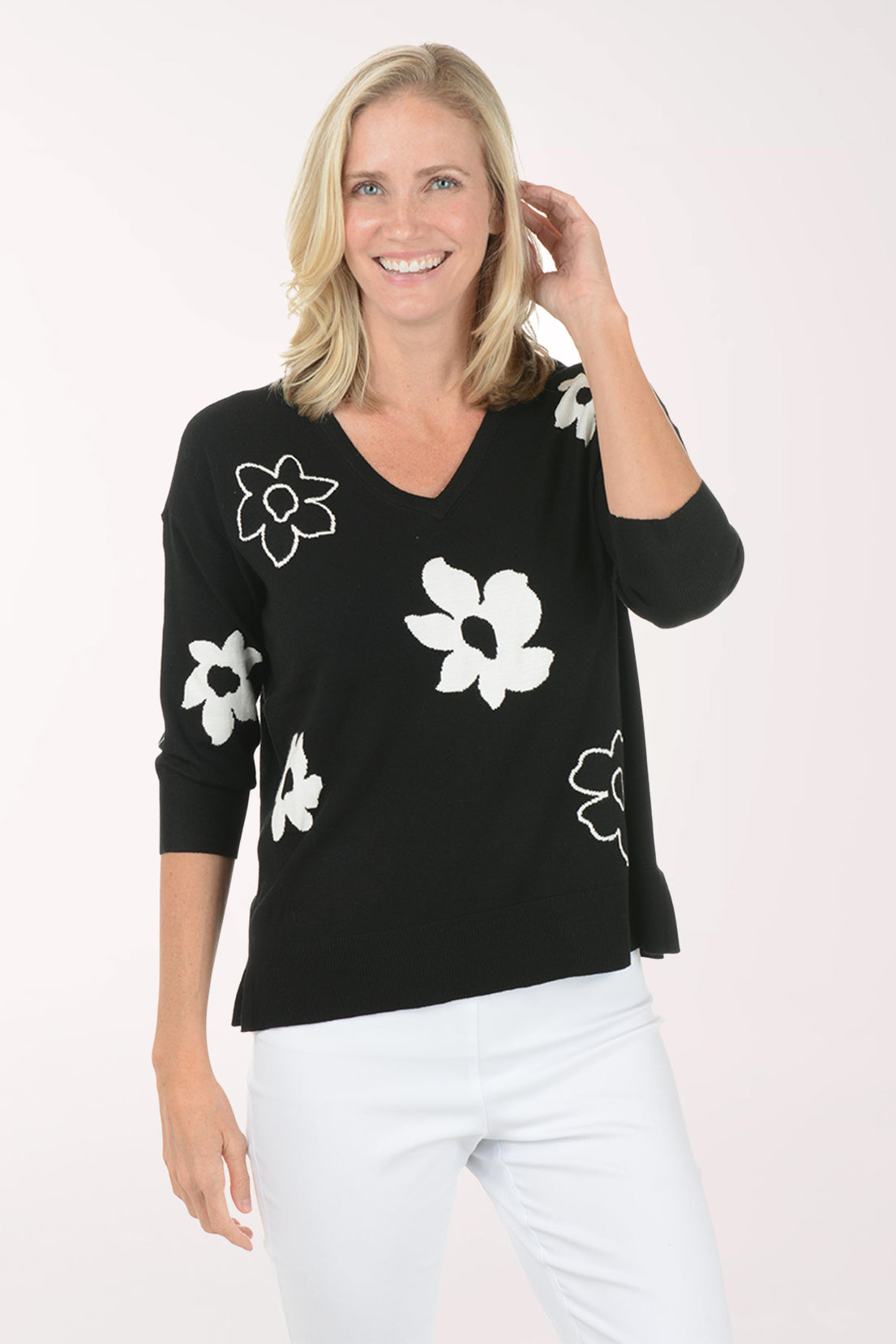 Woman wearing a black sweater with white floral patterns on a white background
