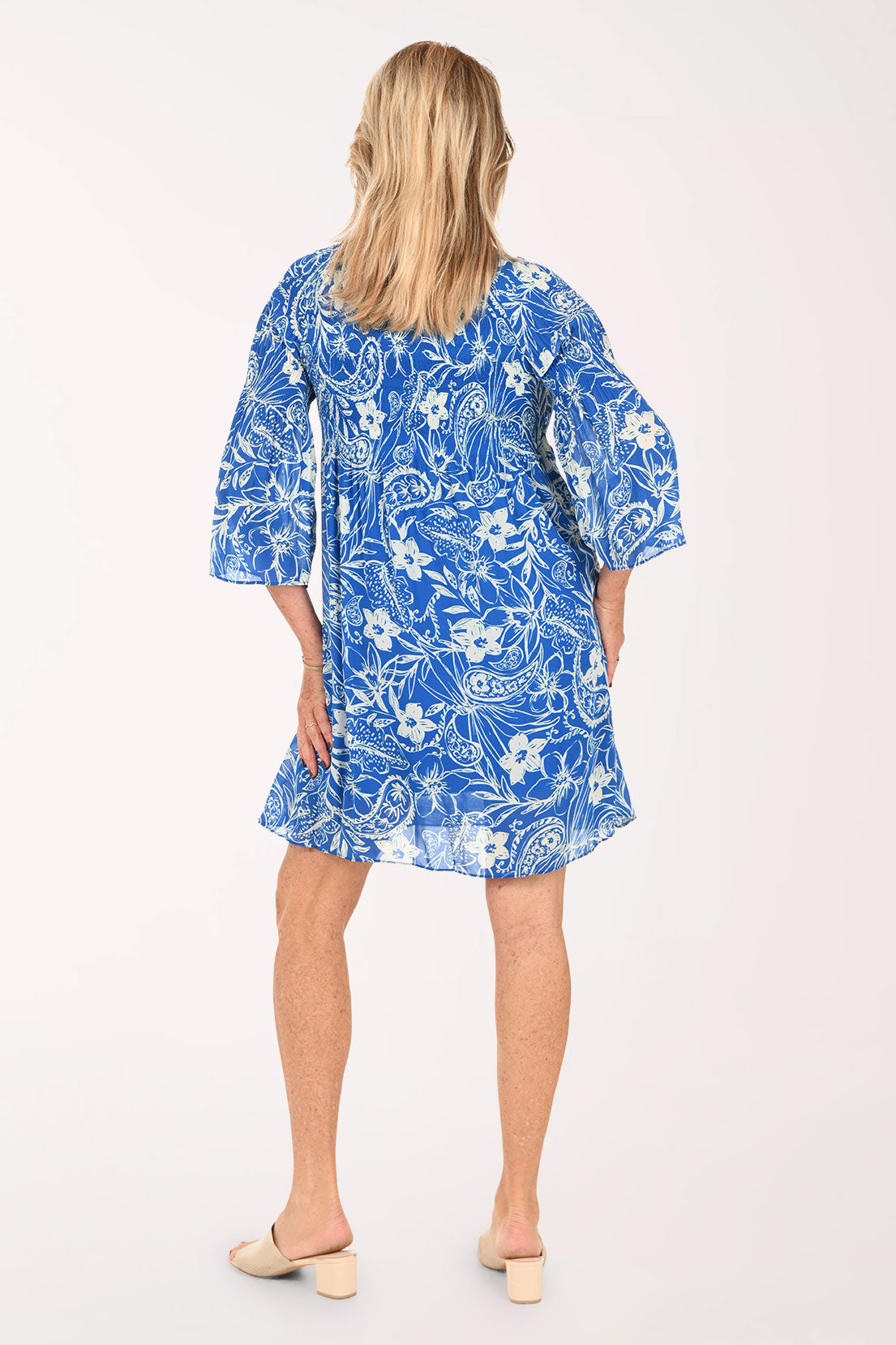 Woman wearing a blue flowy dress with 3/4 sleeves and a flower print