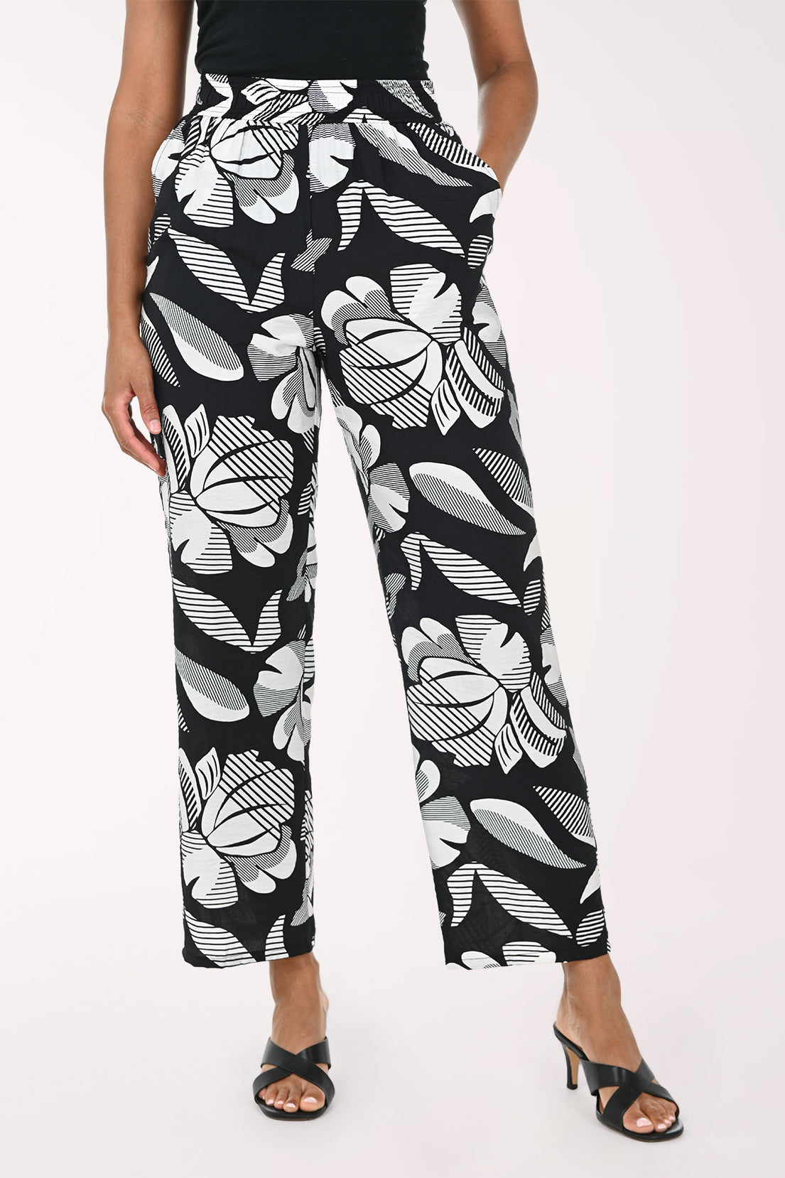 Black pants with white abstract pattern worn by a person on a white background