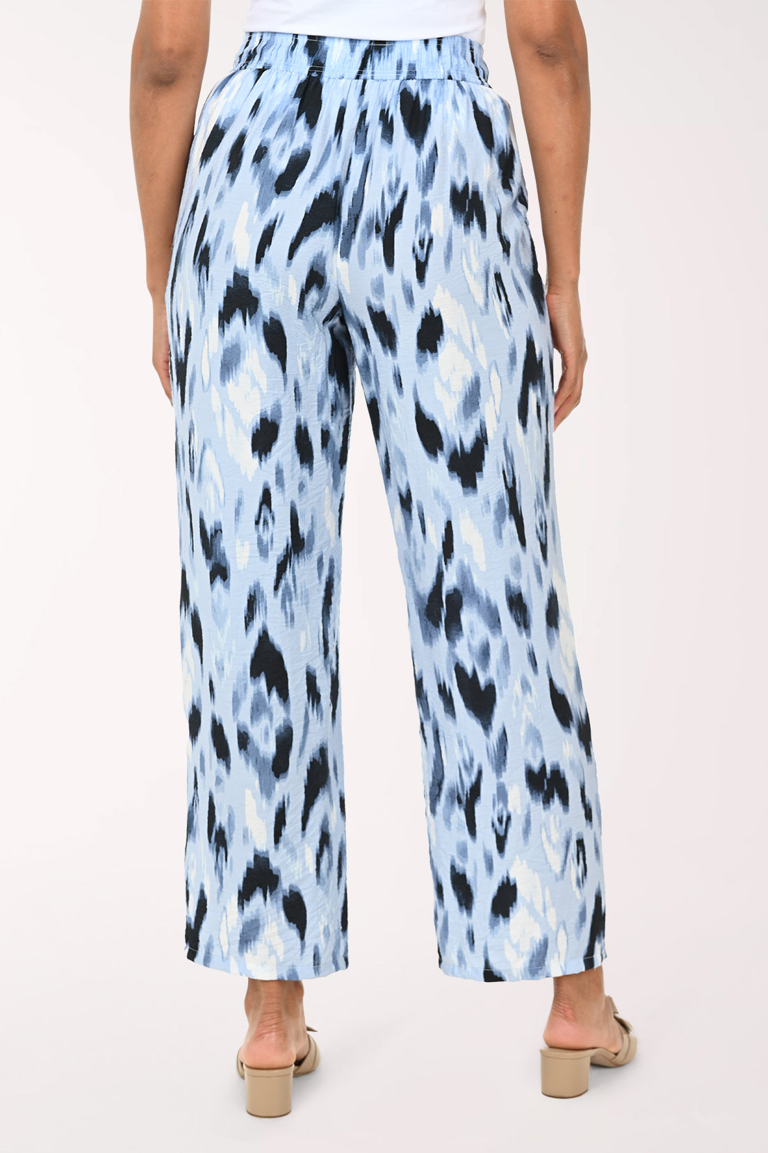 Light blue pants with black abstract pattern worn by a person on a white background