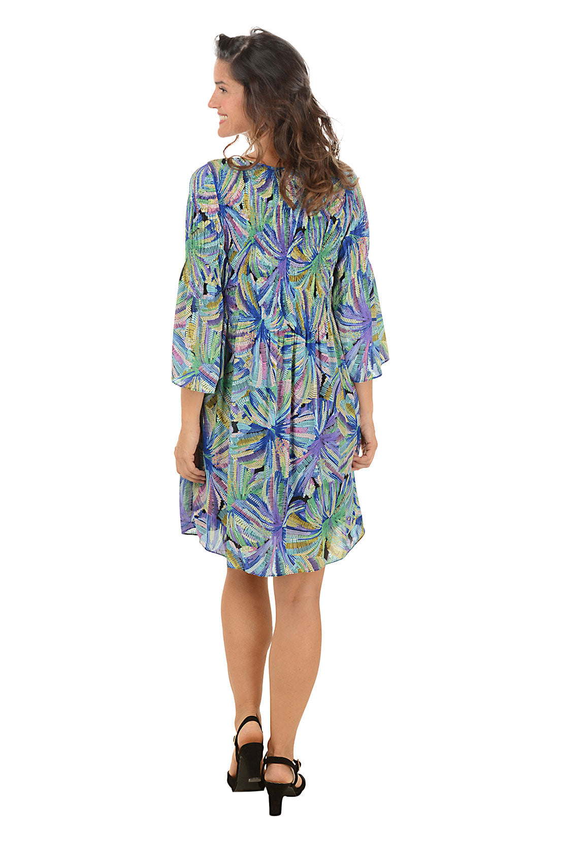 Woman wearing a colorful floral dress on a white background. Back shot.