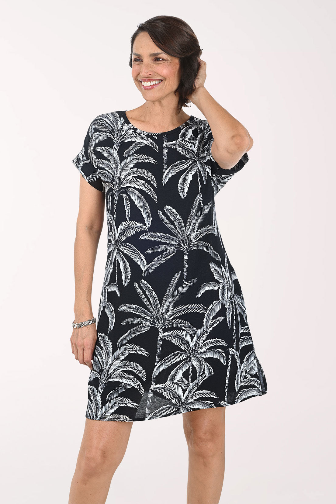 Woman wearing a black dress with white palm tree pattern on a white background
