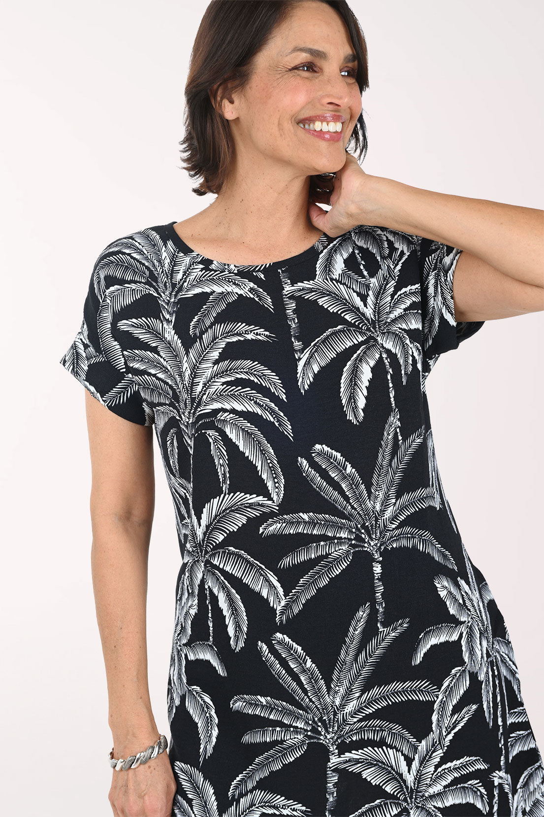 Woman wearing a black dress with white palm tree pattern on a white background