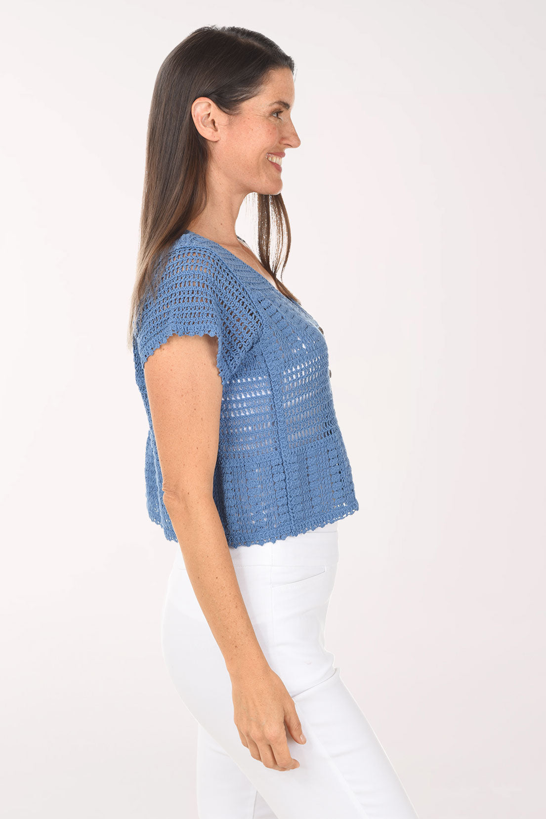 Woman wearing a blue crochet top with buttons on a white background