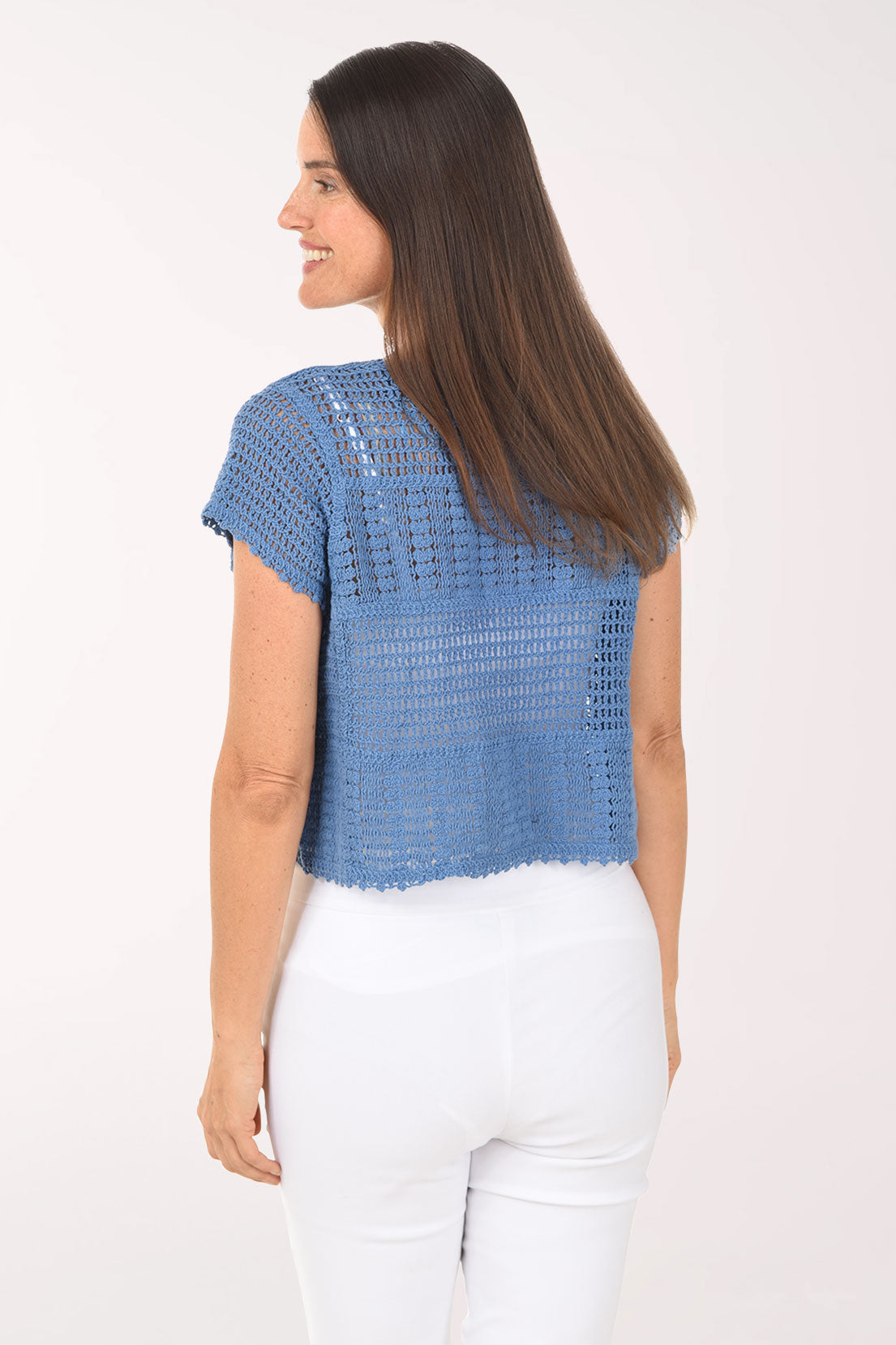 Woman wearing a blue crochet top with buttons on a white background