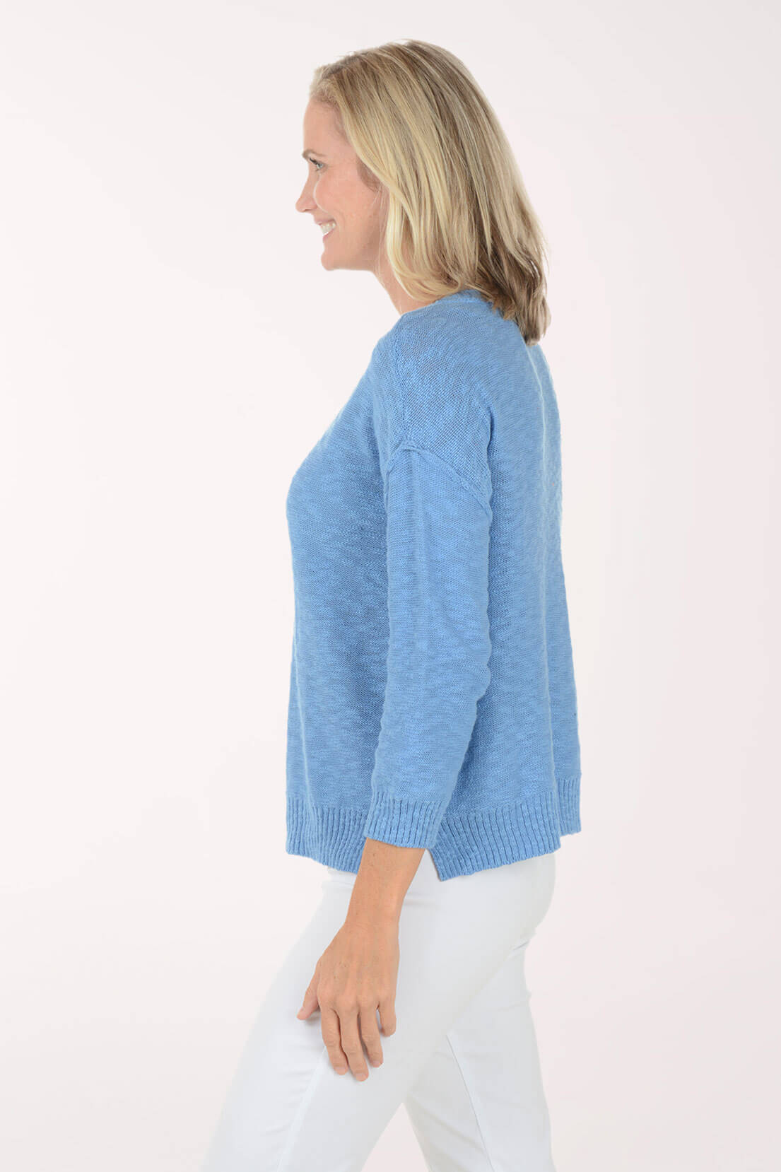 Side shot of Model wearing a Light blue V-neck knit top with three-quarter sleeves and white pants.