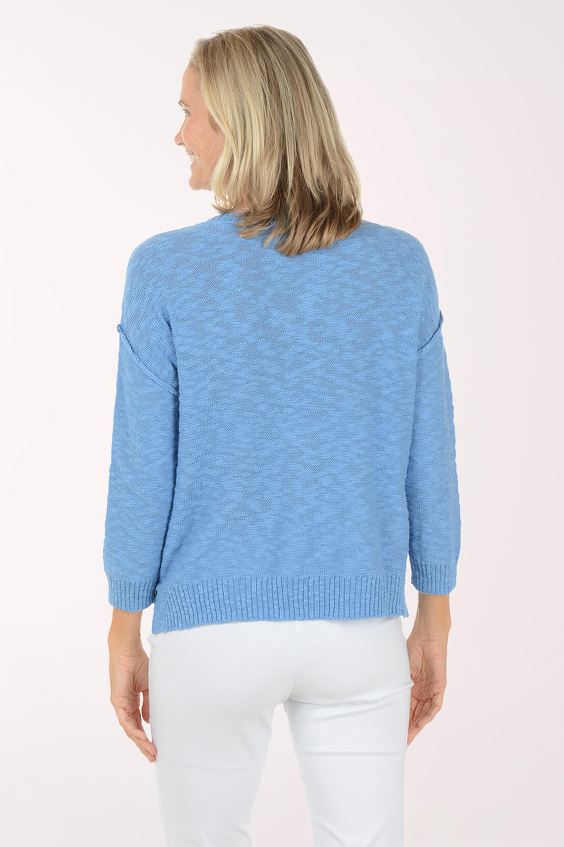Back shot of Model wearing a Light blue V-neck knit top with three-quarter sleeves and white pants.