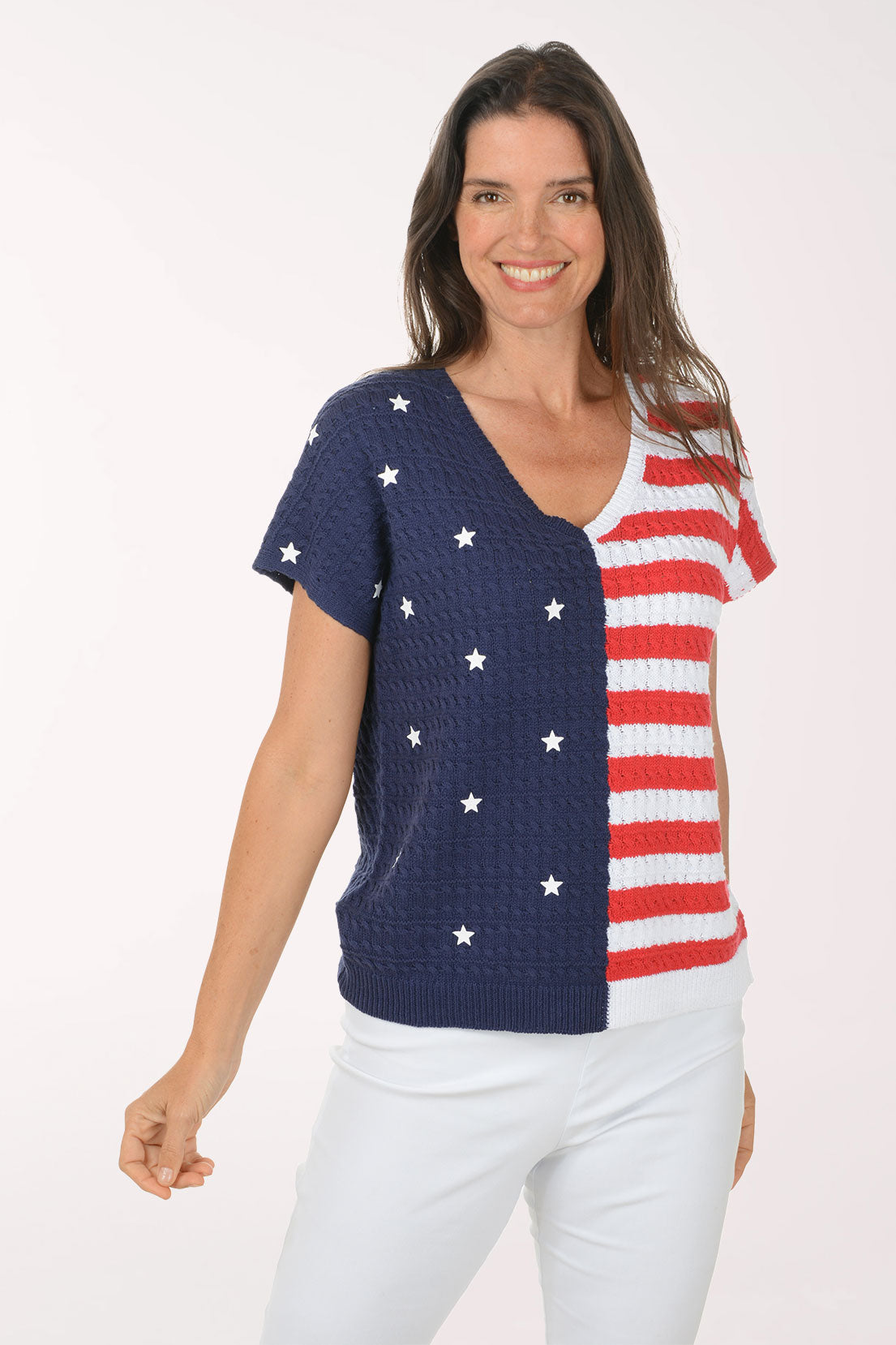 Woman wearing a colorful short-sleeve top with a pattern resembling the American flag on a white background
