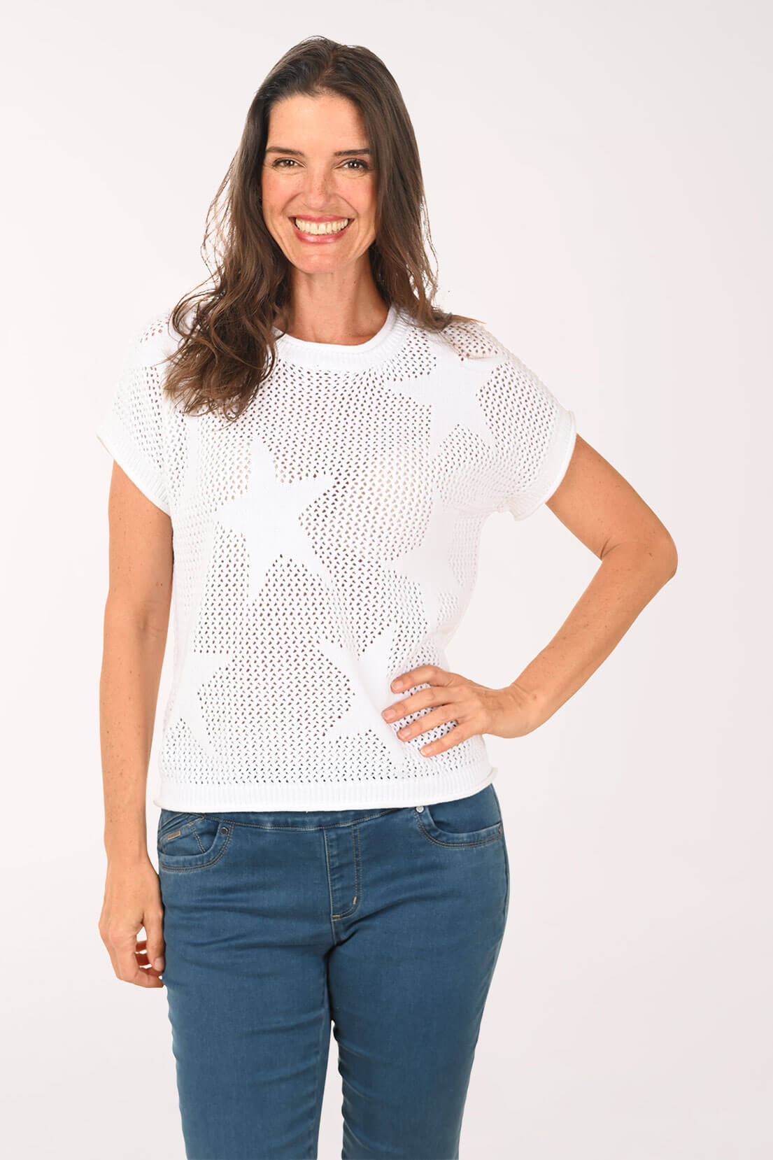 Woman wearing a white star-patterned sweater and blue jeans on a white background