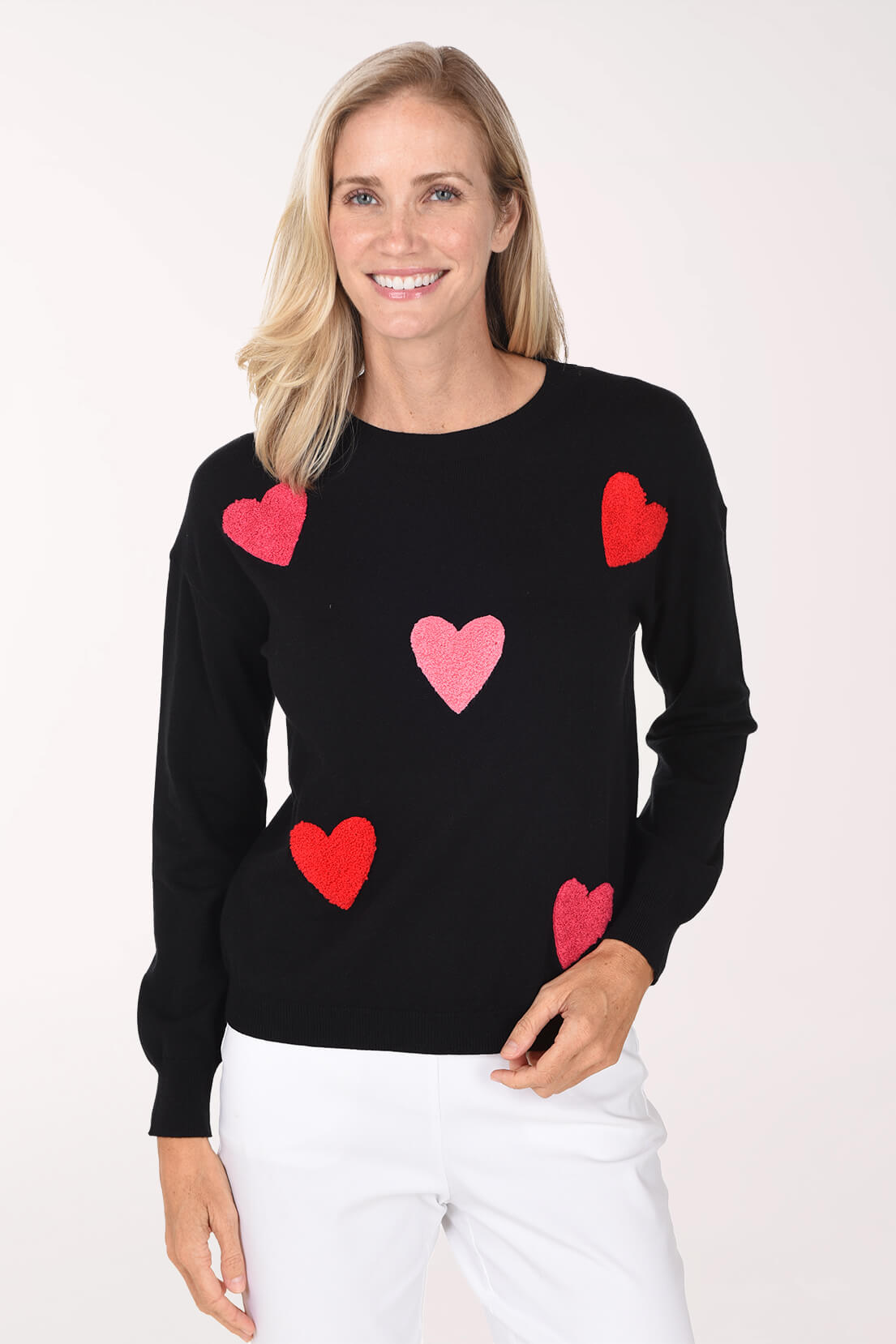 Model wearing a black sweater featuring a playful red and pink heart pattern.