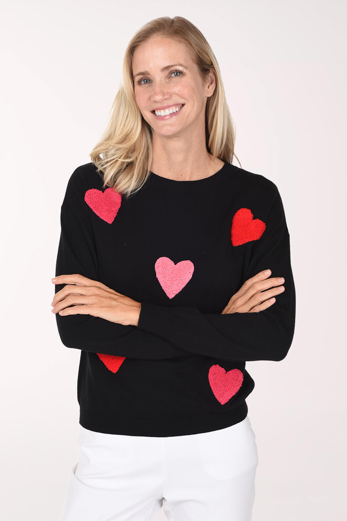 Model wearing a black sweater featuring a playful red and pink heart pattern.