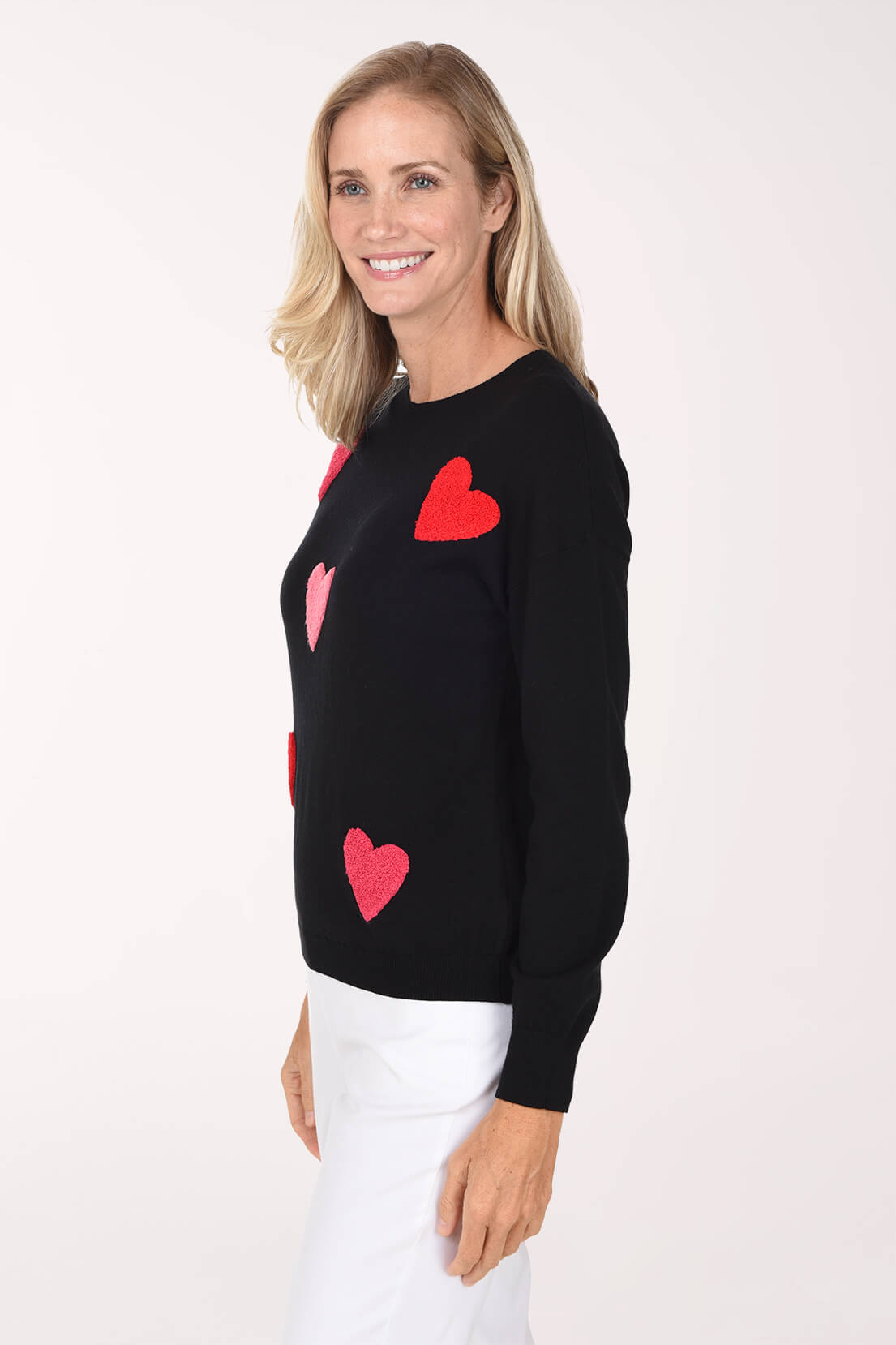 Model wearing a black sweater featuring a playful red and pink heart pattern.