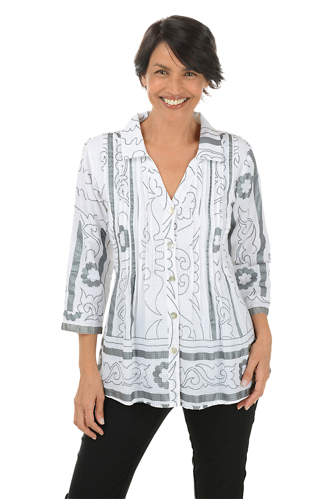 A front shot of a model wearing a pleated button-front shirt with a foldover collar, 3/4 sleeves with cuffs, and a flared hemline. The shirt is printed with a geometric pattern and the person is smiling.