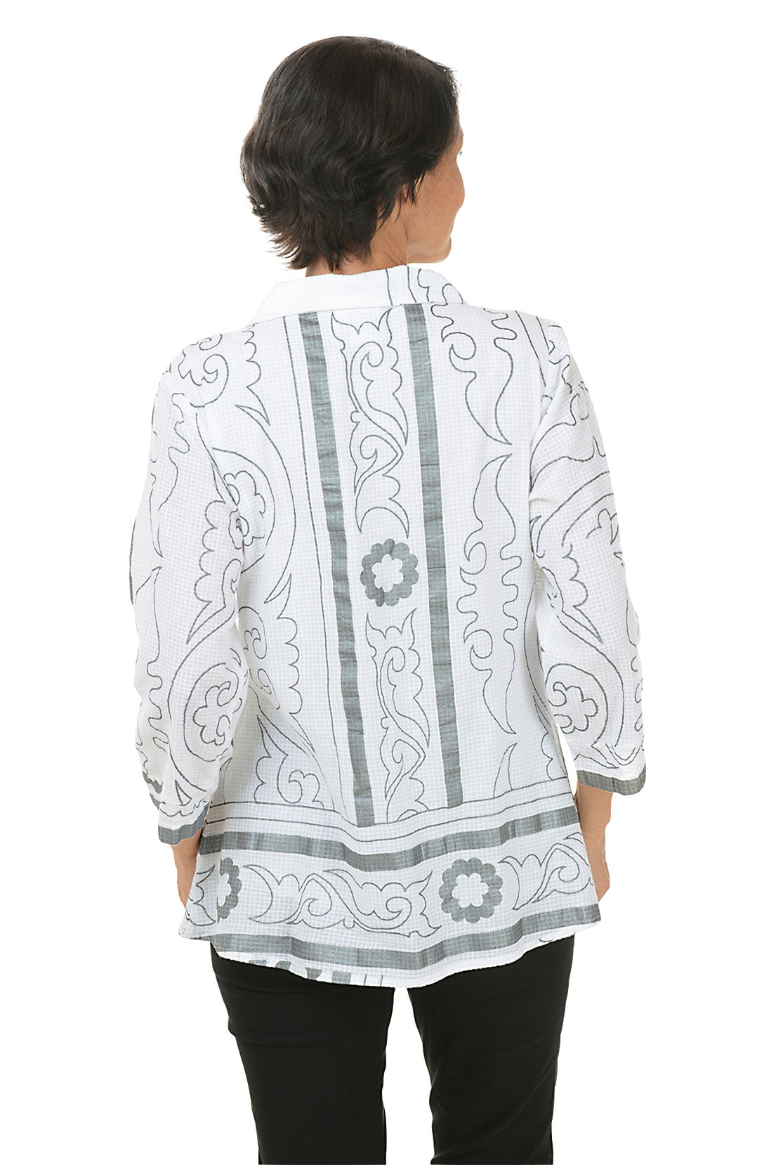 A back shot of a model wearing a pleated button-front shirt with a foldover collar, 3/4 sleeves with cuffs, and a flared hemline. The shirt is printed with a geometric pattern and the person is smiling.
