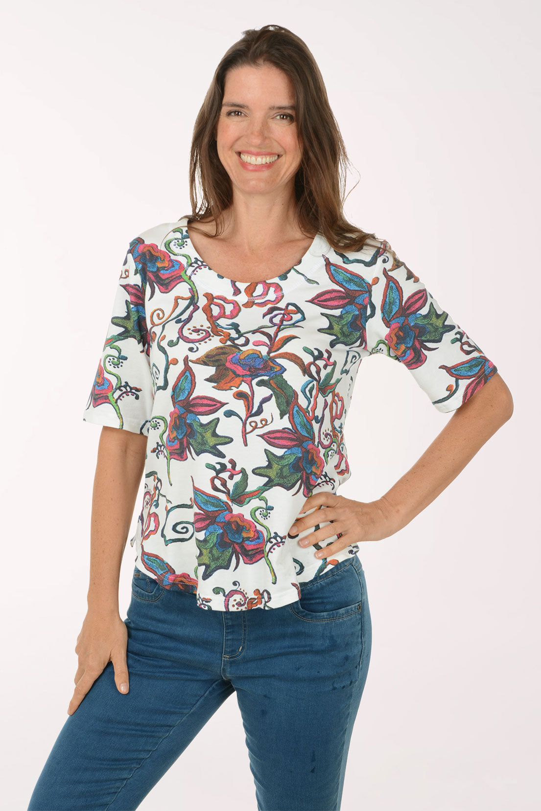 Woman wearing a colorful floral blouse and blue jeans on a white background