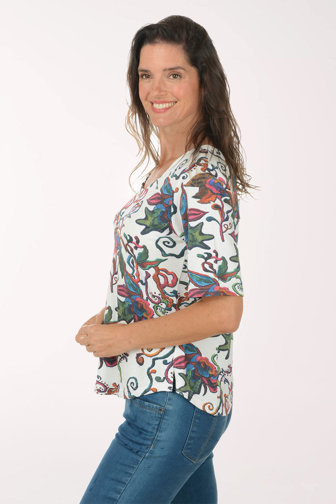 Woman wearing a colorful floral blouse and blue jeans on a white background