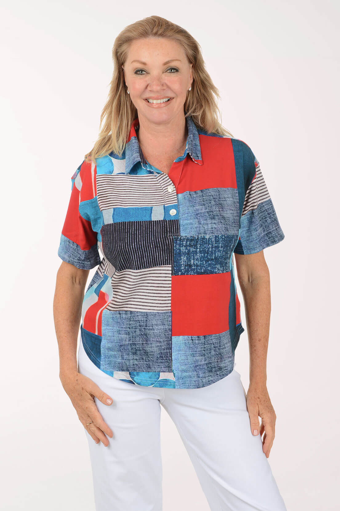 Woman wearing a colorful patchwork shirt with white pants on a white background