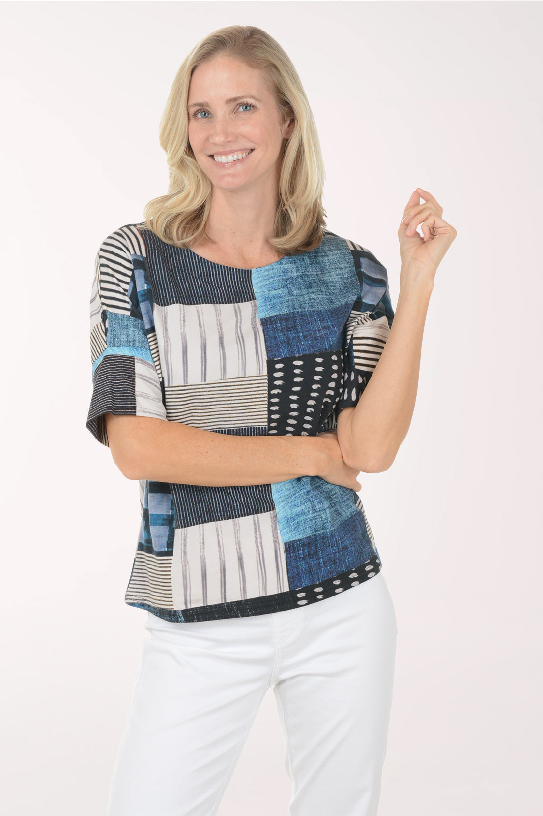 Woman wearing a patchwork top with blue, black, and white patterns on a white background
