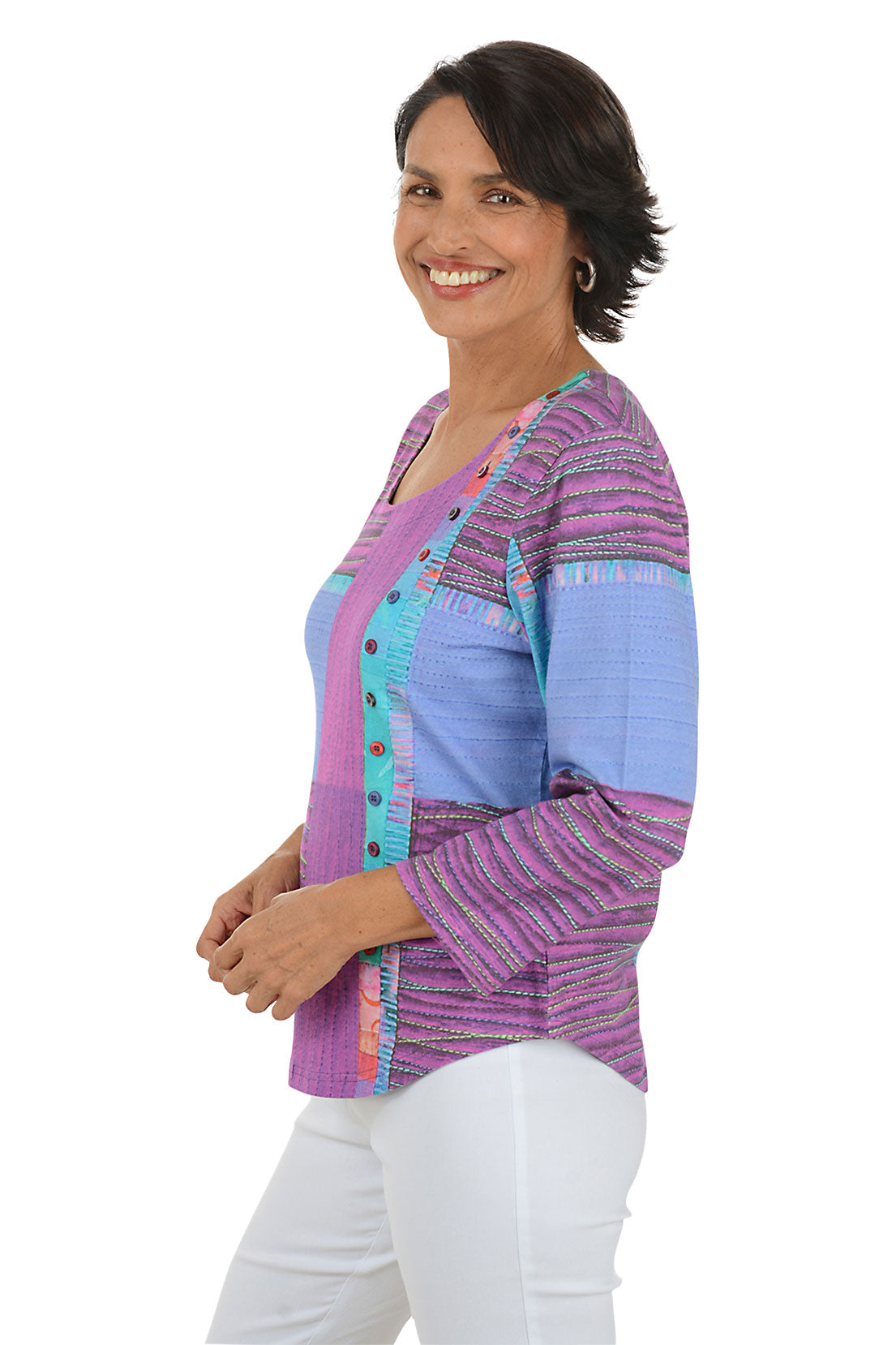 Woman wearing a colorful patterned top with white pants on a white background