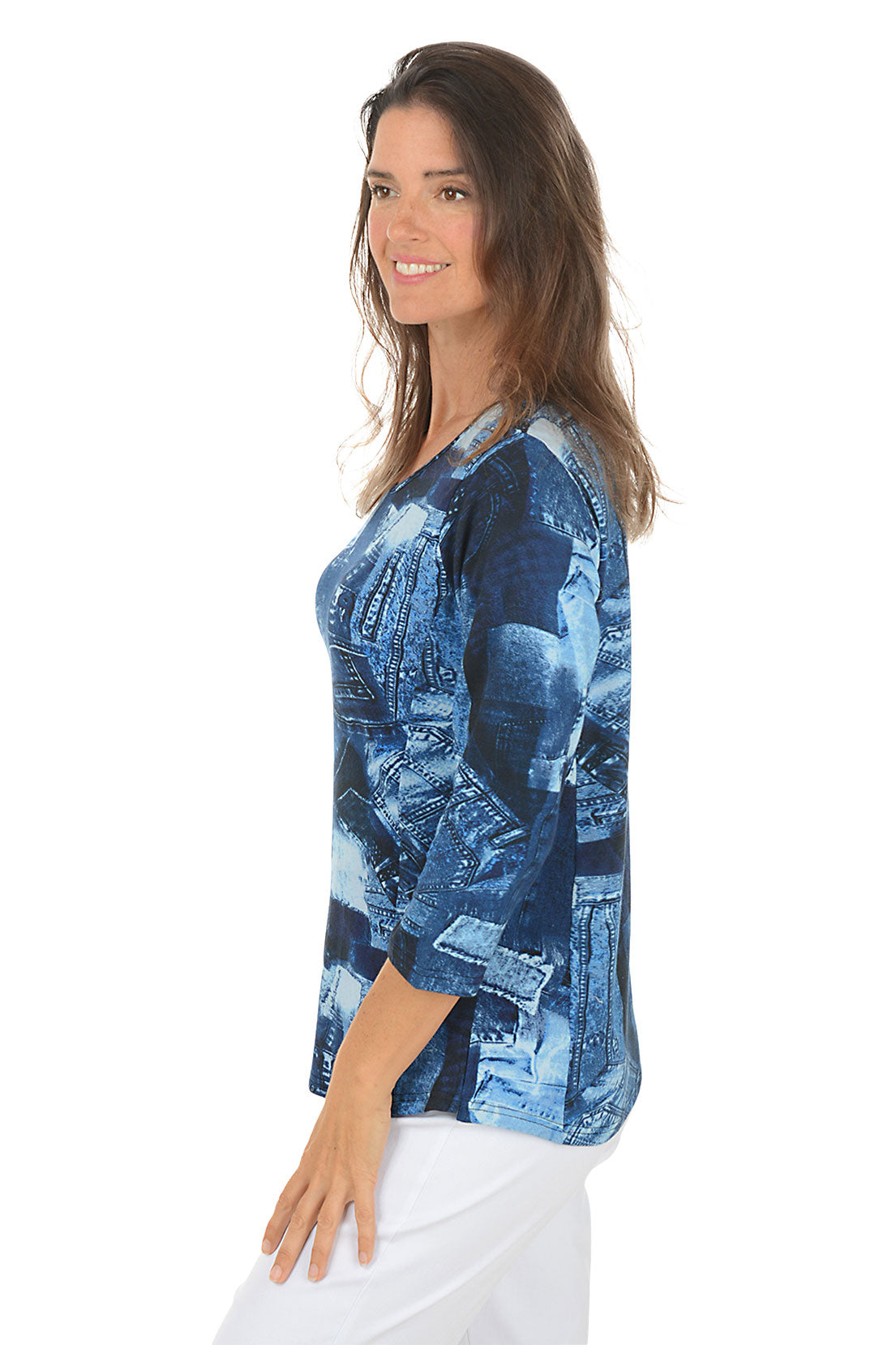 Woman wearing a 3/4 sleeve blue patterned top with white pants on a white background. Side shot.