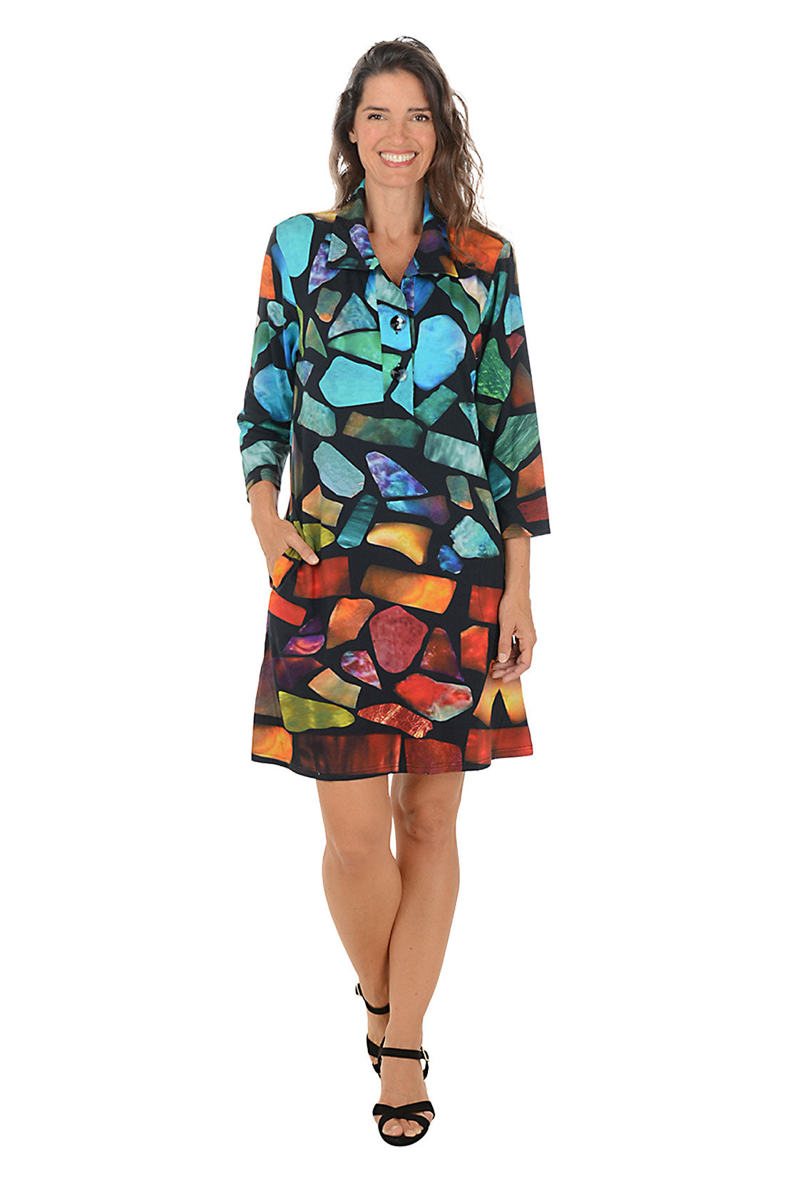 Woman wearing a 3/4 sleeve colorful abstract patterned dress with pockets on a white background.