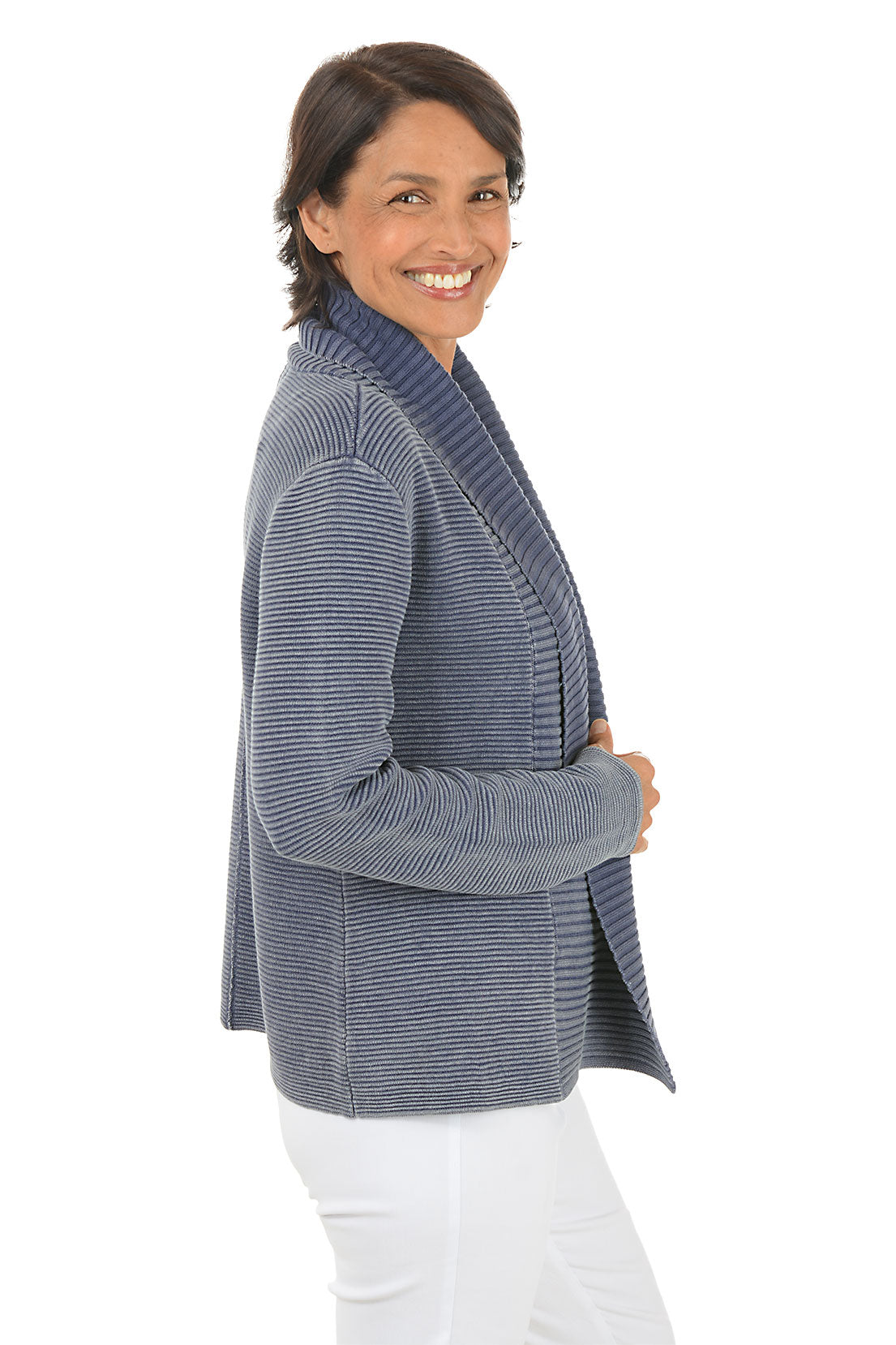 Woman wearing a blue knitted cardigan over a white top on a white background. Side shot.