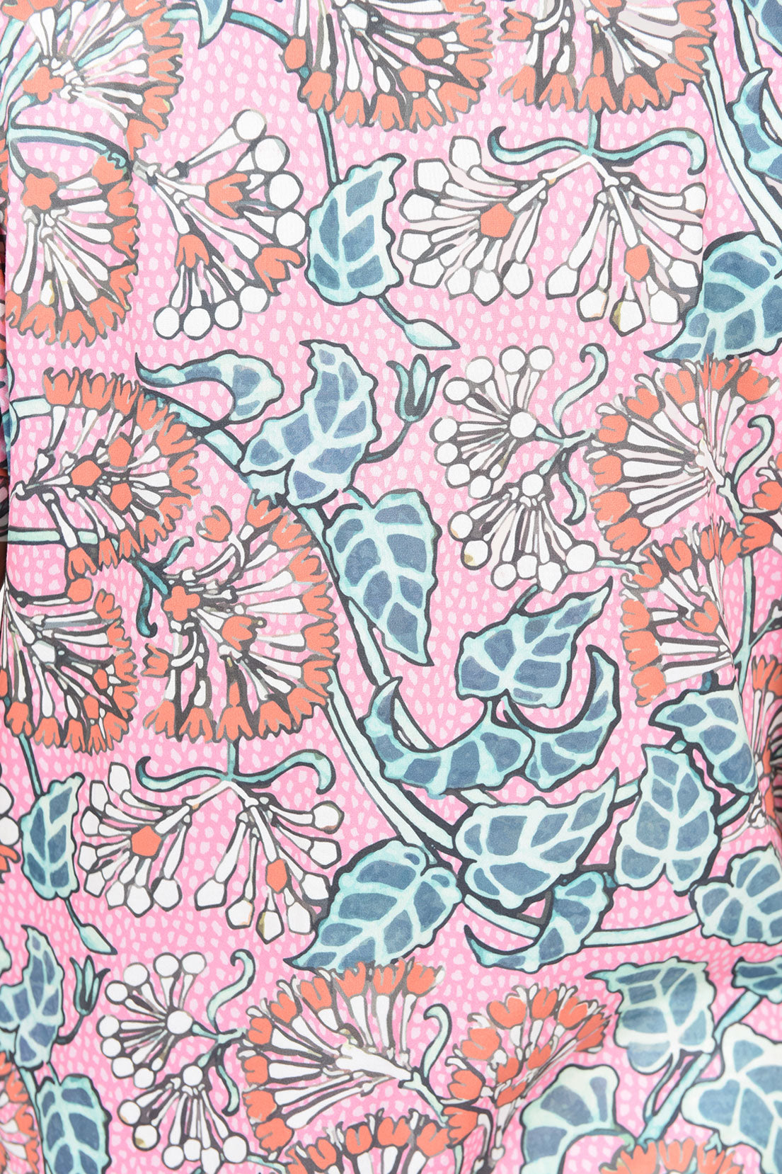 A close-up of a pink patterned fabric featuring stylized floral motifs in coral orange, dusty blue, and white with a subtle polka-dot background.