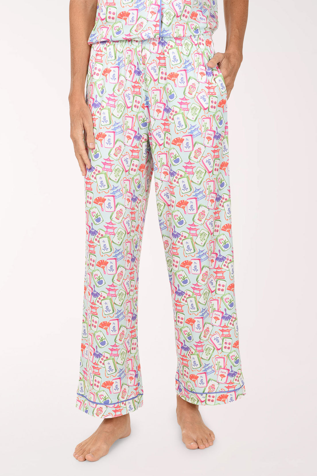 A person wearing loose, wide-leg pajama pants with a colorful abstract print on a white base, shown from the waist down against a plain light background.