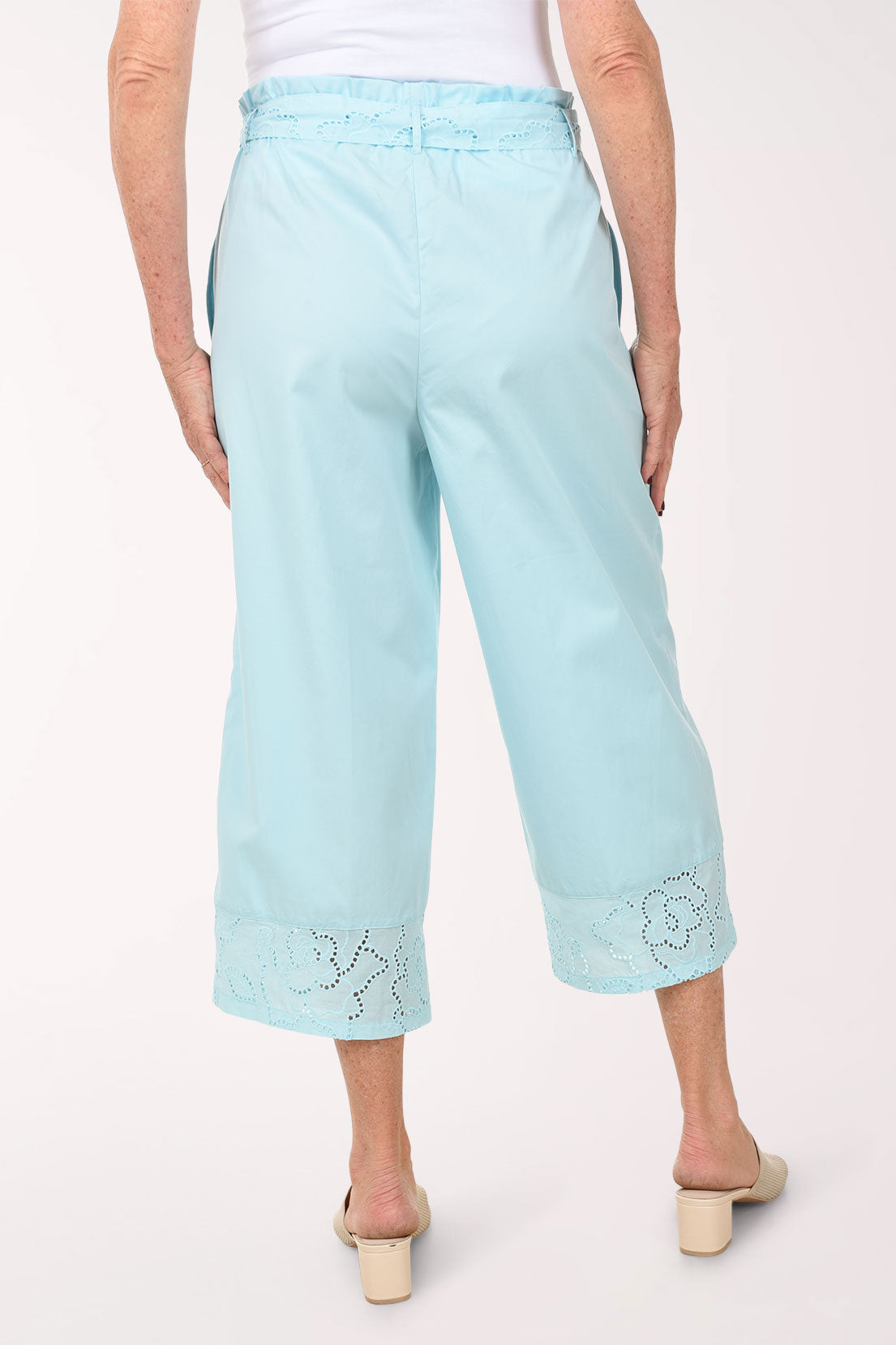 Light blue pants with lace details worn by a person on a white background