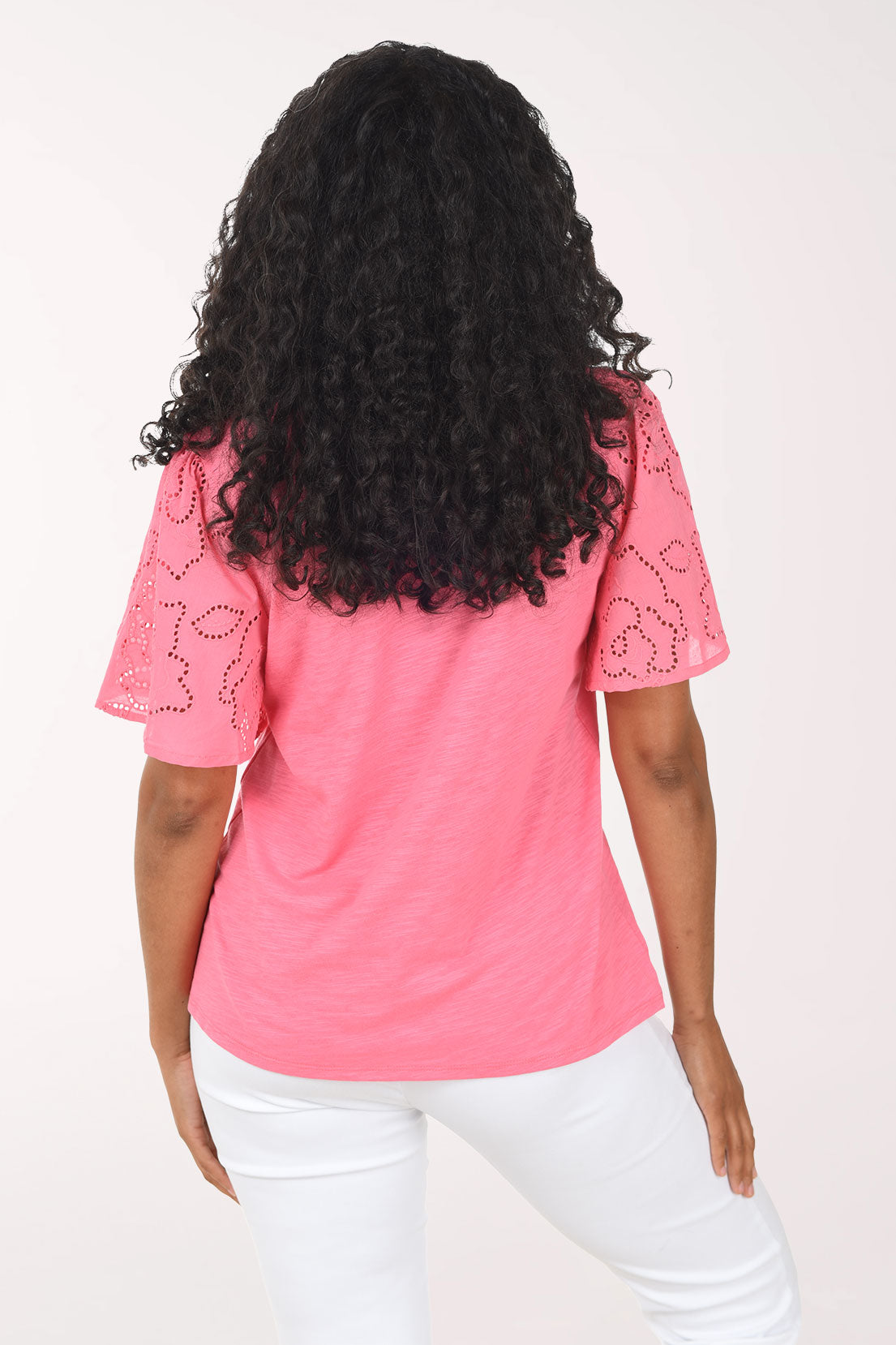 Woman wearing a pink blouse with floral lace sleeves on a white background