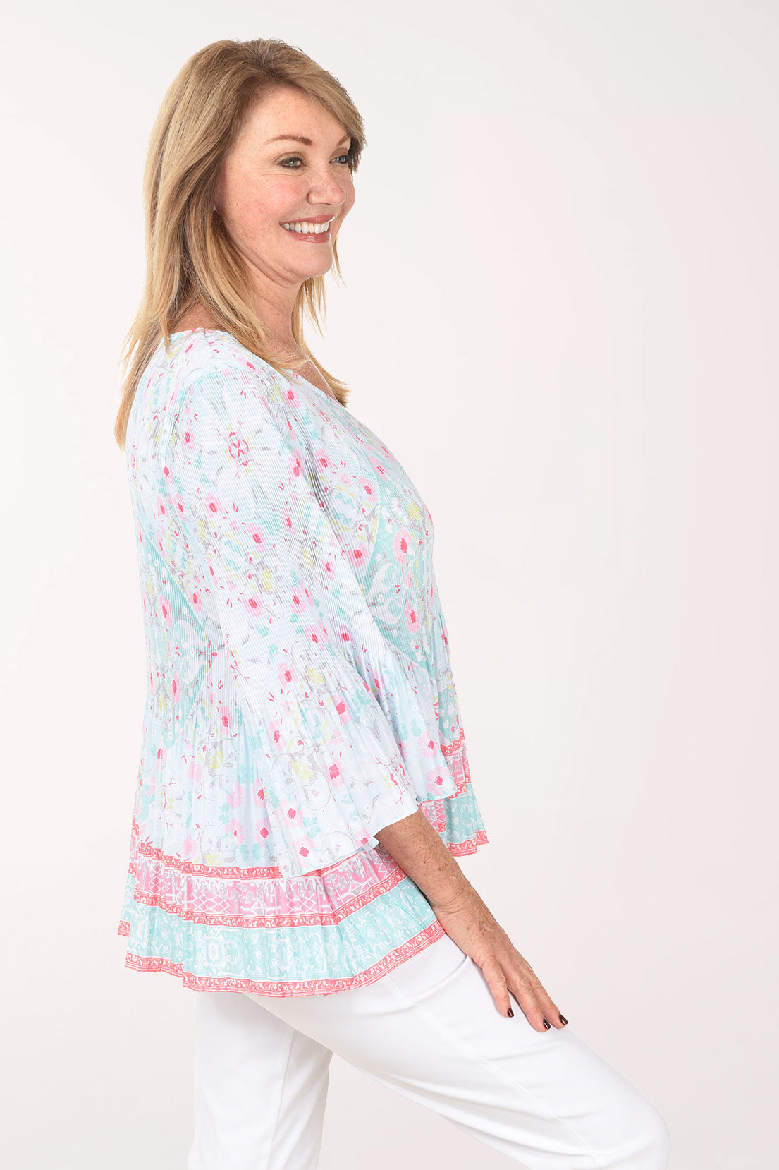 Woman wearing a light blue floral print top with pink trim on a white background