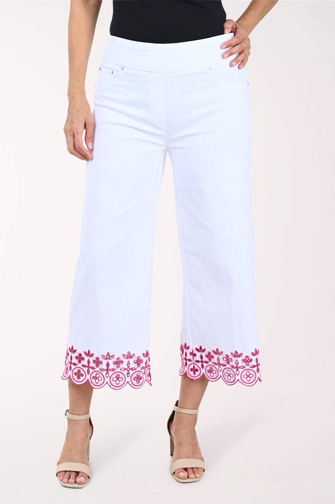 White pants with pink floral embroidery on a white background